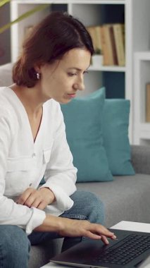 Kadınlar rahat bir oturma odasında kanepede otururken dizüstü bilgisayarda yazarlar..