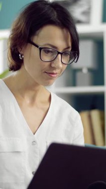 Kadın evde dizüstü bilgisayarda çalışıyor, ışık odasında, uzaktan çalışma konsepti.