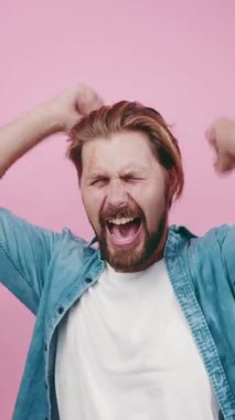 Adam pembe arka plan ve kot gömlekli samimi bir andan zevk alıyor, neşe ifade ediyor..