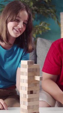 Başka bir kadın rahat bir oturma odasında gülümserken bir kadın tahta blokları dizer..