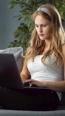 Kadınlar evde otururken dizüstü bilgisayarda yazarlar. Doğal ışık odayı dolduruyor..