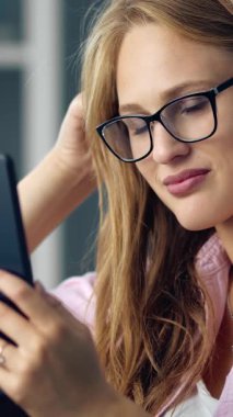 Genç bir kadın gündüz vakti kapalı alanda akıllı telefonlara bakarken gülümsüyor..