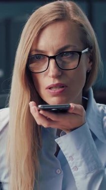 Ofisteki bir iş kadını çalışırken akıllı bir telefonla konuşur..