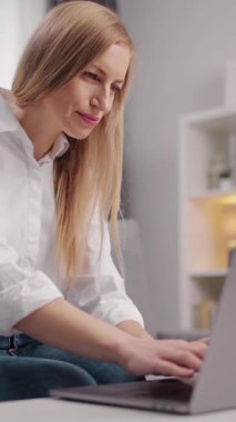 Kadın aydınlık bir odada çalışırken dizüstü bilgisayarına odaklanıyor..