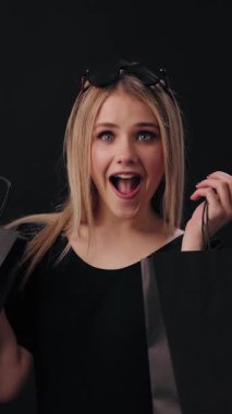 Kadın elinde siyah bir alışveriş çantasıyla alışverişe çıkınca neşesini gösteriyor..