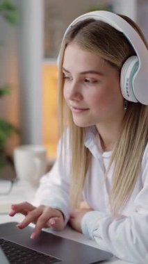 Kadın evde dizüstü bilgisayar ve kulaklıklarla oturuyor, işine odaklanıyor ve daktilo yazıyor..