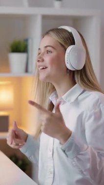 Kadın kulaklık takarken dans ediyor, kapalı bir ortamda müziğin tadını çıkarıyor..