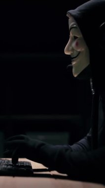 Maskeli bir adam karanlık bir odada eldiven takıyor..