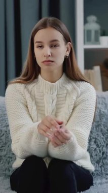 Kadın evinde kanepede oturuyor ve başı ağrıdığı için başını tutuyor..