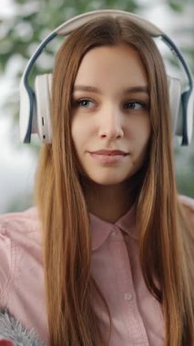 Kadın, gülümseyen ve rahatlatan parlak bir odada kulaklıkla müzik dinliyor..