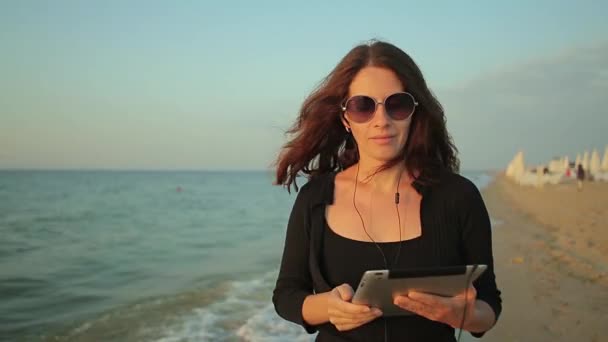 Женщина использует планшетный ПК на берегу моря — стоковое видео
