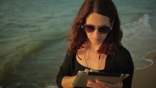 Женщина использует планшетный ПК на берегу моря — стоковое видео