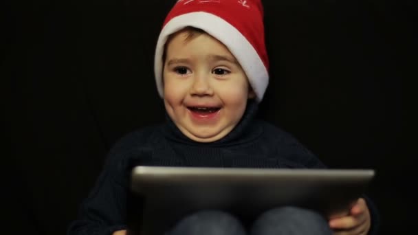 Маленький мальчик с удовольствием держит в руках планшетный компьютер — стоковое видео