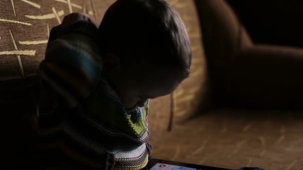 Kleiner Junge in Kapuze blättert auf Tablet-PC — Stockvideo