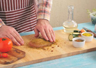 man prepares a chicken breast in a spicy spices