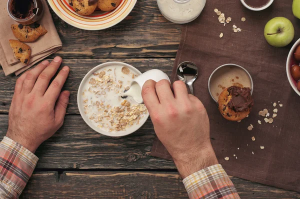 Man eating breakfast oatmeal with cookies and coffee — Stock Photo, Image