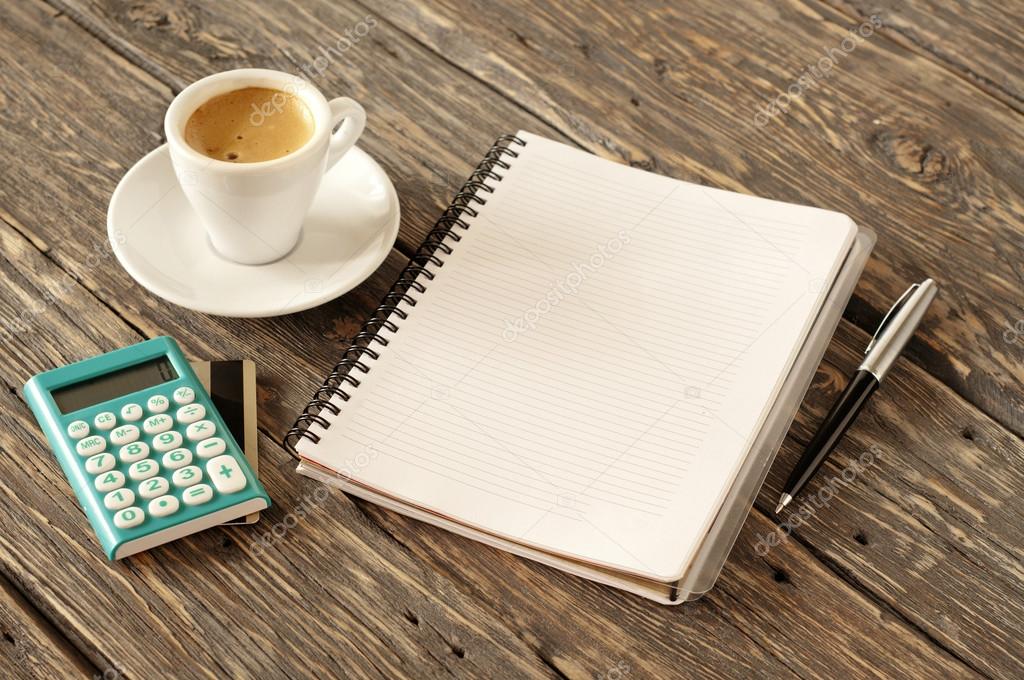 open notepad with pen, coffee, calculator with gold credit card