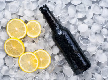 Dark beer bottle with lemon slices in the ice clipart