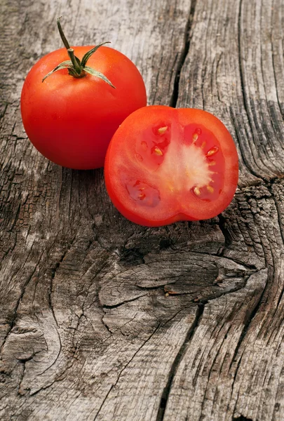 Tomate vermelho inteiro com fatia de tomate no fundo de madeira — Fotografia de Stock