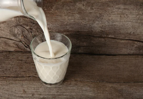 Hälla mjölk från en karaff i glas — Stockfoto