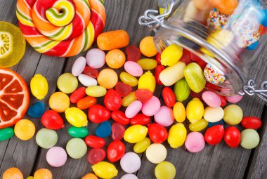 Colorful candies scattered on the wooden table clipart