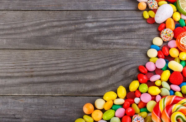 Красочные конфеты разбросаны по деревянному столу — стоковое фото