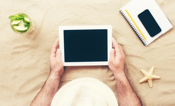Man holding tablet with blank screen lying on the beach — Stock Photo, Image