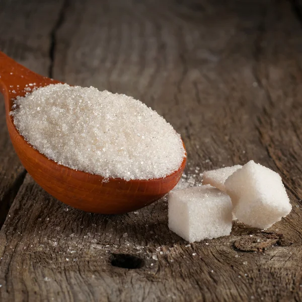 Azúcar blanco en cuchara de madera con cubos de azúcar —  Fotos de Stock