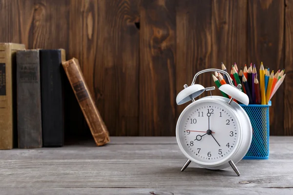 Eski kitaplar ve renkli kalemler ile beyaz çalar saat