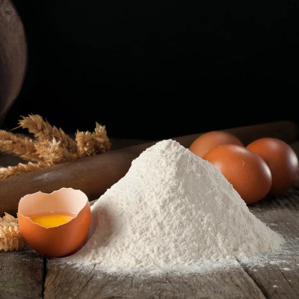 Un puñado de harina de trigo con huevos marrones crudos rotos —  Fotos de Stock