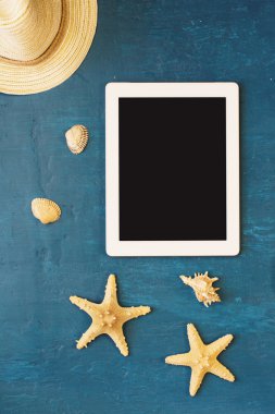 Beyaz boş ekran, hasır şapka, kabukları ve deniz yıldızı ile tablet