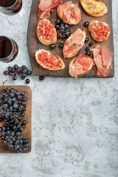 Bruschetta and sandwiches with ham with two glasses of wine — Stock Photo, Image
