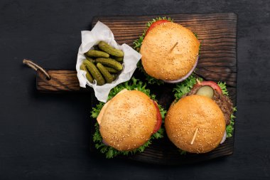 Turşu ile masif ahşap tahta üzerinde üç farklı burger