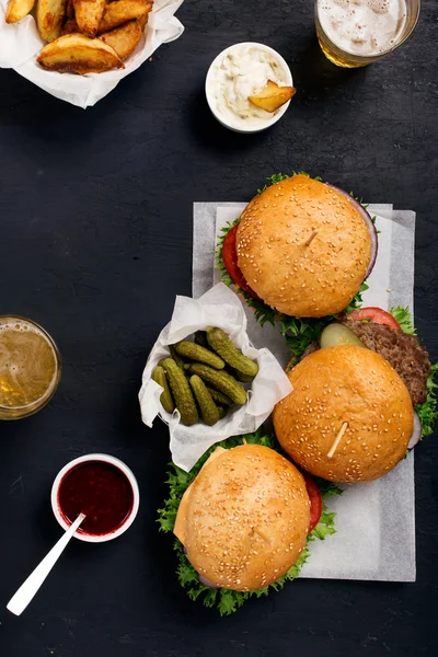 Hamburgery i kanapka na ciemnej powierzchni z piwo i frytki — Zdjęcie stockowe