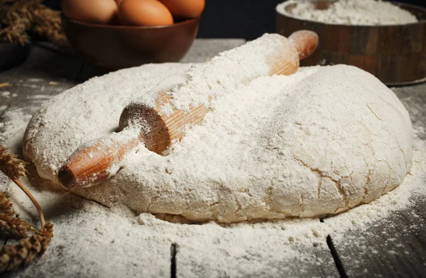 Dough with wooden rolling pin close up on wooden table — Stock Photo, Image