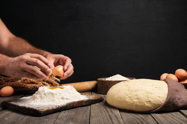 Мужские руки разбивают яйцо на муку для приготовления хлеба — стоковое фото