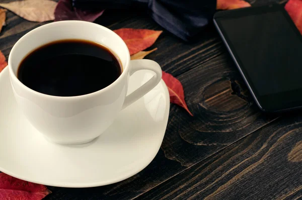 Kop koffie op houten tafel met herfst droge bladeren — Stockfoto