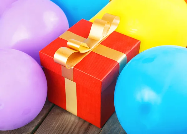 Gran caja de regalo roja con cinta dorada con globos — Foto de Stock