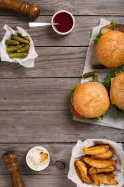 farklı hamburger sosları, patates ve pickl ahşap tablo