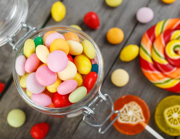 Különböző színes candy üvegedénybe, a fából készült asztal — Stock Fotó