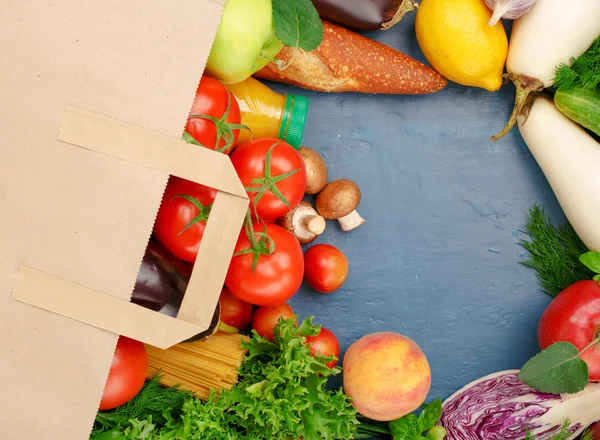 Sac en papier avec légumes et fruits sur la surface bleue — Photo