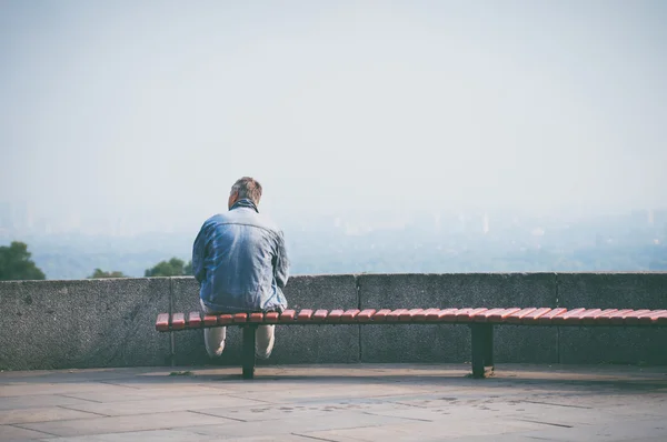Старик сидит на скамейке на городской смотровой площадке — стоковое фото