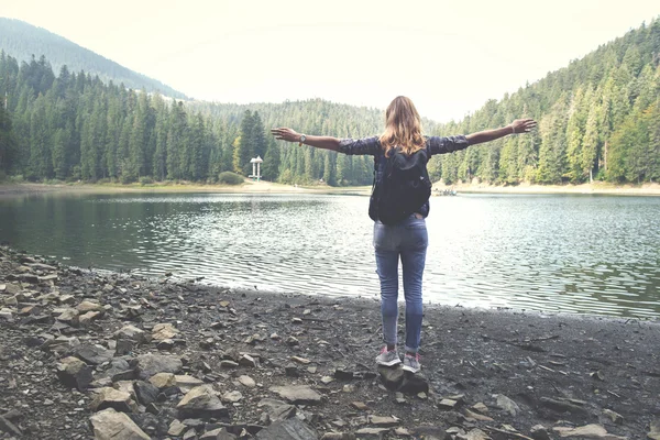 Mladá dívka stojí nedaleko horské jezero šíření ruce — Stock fotografie