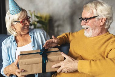 Neşeli son sınıf çifti birlikte tatil yapıyor. Mutlu yaşlılar hediyelerini verir. Doğum günü kavramı veya yıldönümü kavramı