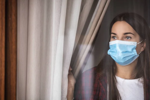 Droevige Jonge Vrouw Met Een Medisch Masker Blijft Geïsoleerd Thuis — Stockfoto
