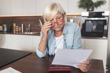 Emekli, aylık bütçesini planlıyor. Vergi giderleri olan kağıt tutar