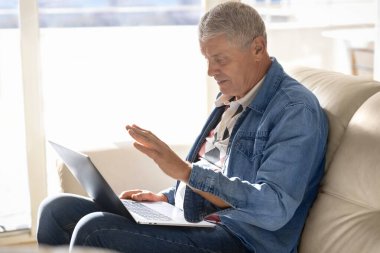 Evdeki kanepede oturan yaşlı bir adam ailesiyle veya arkadaşlarıyla konuşmak için internet teknolojisini kullanıyor. Yaşlı bir adam sevdikleriyle video konferansı yoluyla iletişim kurar.