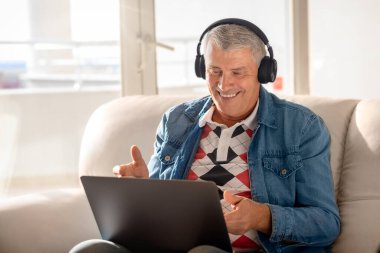 Evdeki koltukta oturan mutlu yaşlı adam ailesiyle ya da arkadaşlarıyla konuşmak için internet teknolojisini kullanıyor. Yaşlı bir adam sevdikleriyle video konferansı yoluyla iletişim kurar.