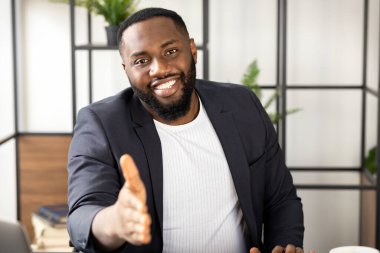 Afrikalı Amerikalı adam el sıkışma konsepti için kameraya uzanan gülümsüyor.