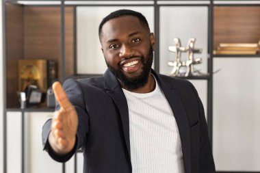 Afrikalı Amerikalı adam el sıkışma konsepti için kameraya uzanan gülümsüyor.